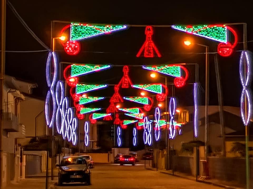 Rua decorada com estruturas de luz coloridas durante uma romaria